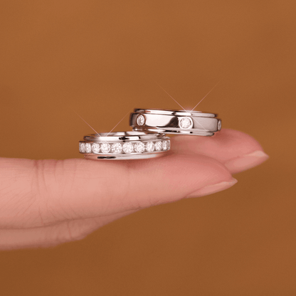 A close-up of the Mozi Twin Sparkle Moissanite Rings, both rings held together on a fingertip against a neutral background, showcasing the sparkling moissanite stones.