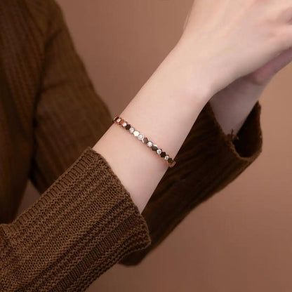 Mozi Beehive Moissanite Bangle worn on a wrist, showcasing its hexagonal gold design with moissanite stones, against a brown background