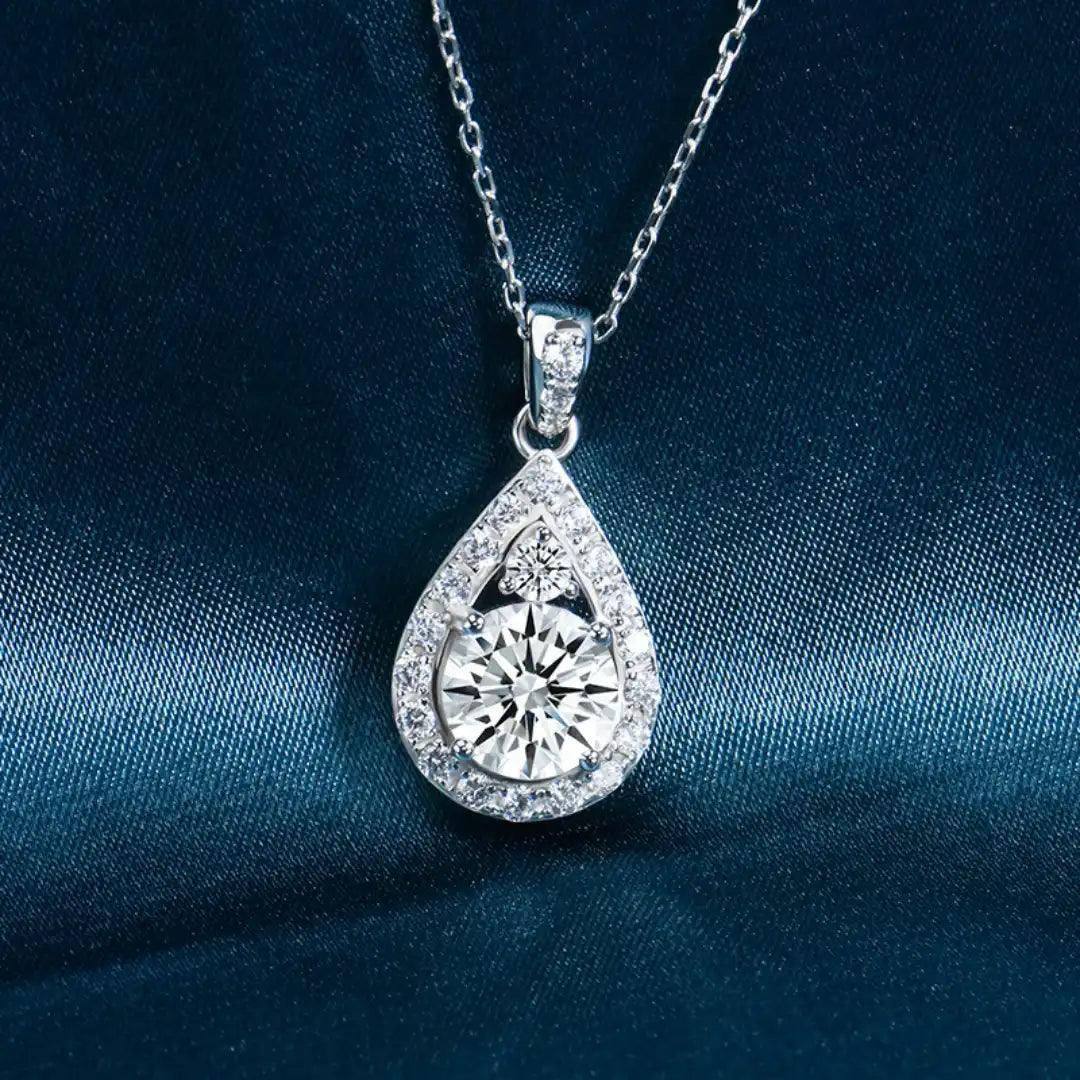 Teardrop Moissanite Necklace close-up against a teal background, focusing on the intricate craftsmanship of the pendant and the brilliance of the central moissanite stone.