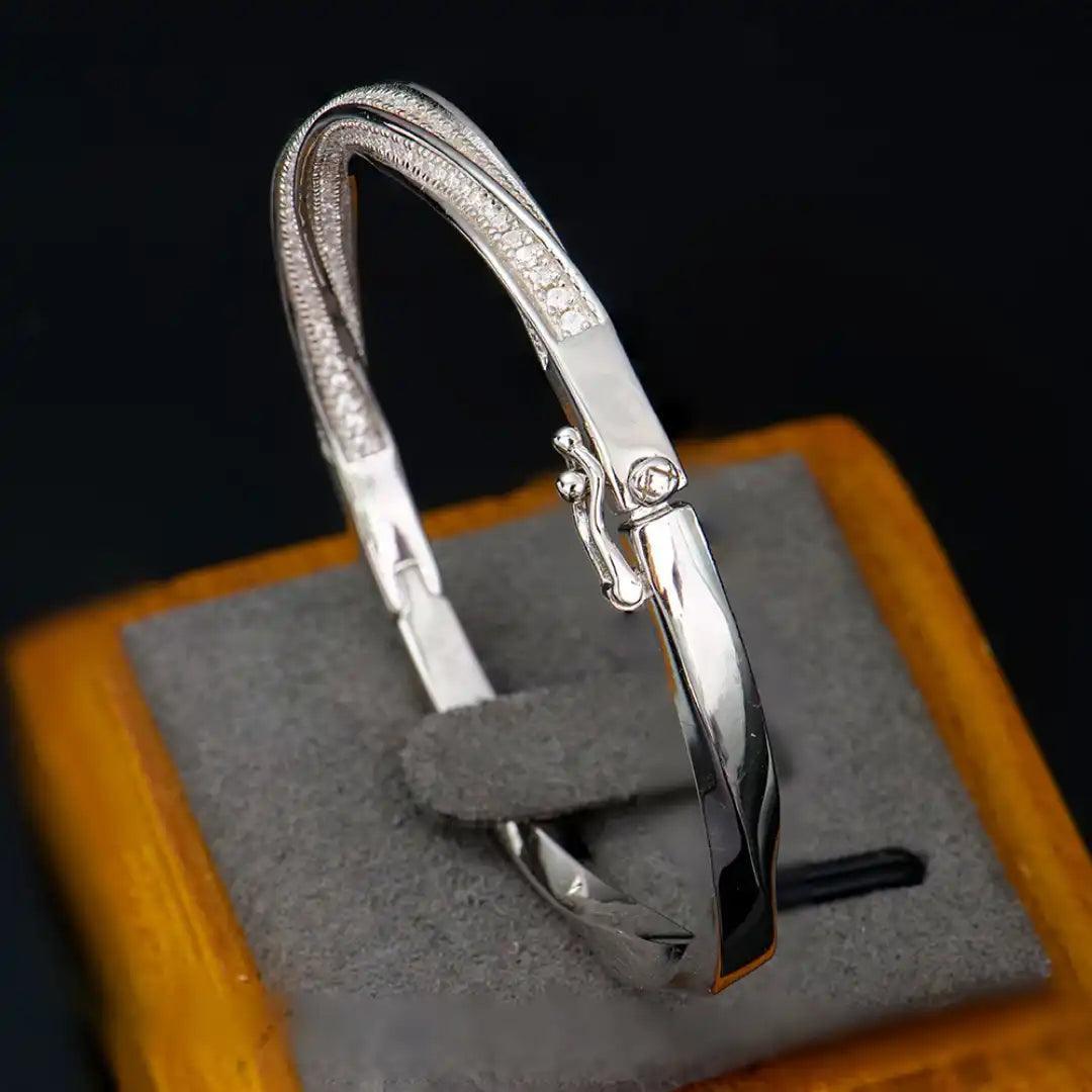 Mozi Mobius Moissanite Bangle displayed on a jewelry stand, featuring a close-up of the S925 silver design with moissanite stones in a Mobius twist