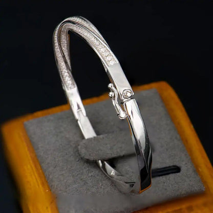 Mozi Mobius Moissanite Bangle displayed on a jewelry stand, featuring a close-up of the S925 silver design with moissanite stones in a Mobius twist