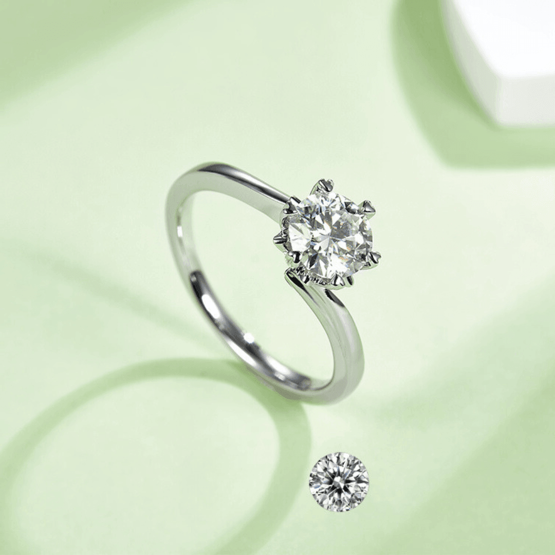 Close-up of the White Flower Moissanite Ring showcasing its brilliant round Moissanite set in a floral design on a light green background.